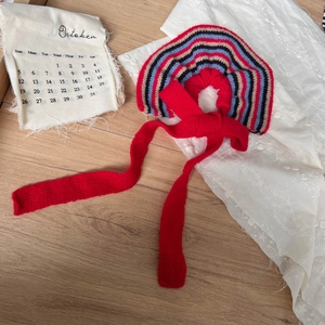 Chic rainbow striped knit hair scrunchie with red ribbons on a cozy wooden background