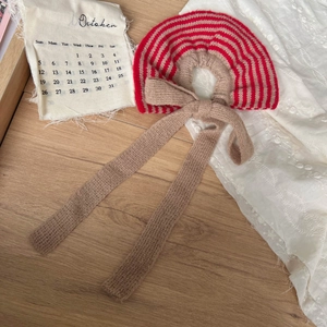 Vintage red and beige striped knit collar for kids with a large bow tie on wooden background