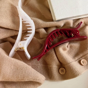 Unregelmäßige Schleifen-Haarklammern in Weiß und Burgunder auf beige Strickpullover
