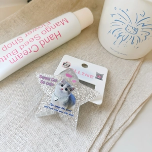 Detailed view of a silver glitter star hair clip featuring a cute cat on a display card