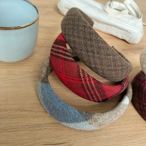 Close-up of three thick plaid wool headbands in brown, red, and blue checkered patterns