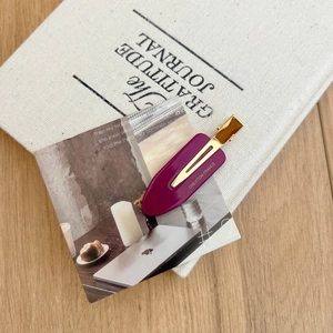 Detail of purple French acetate hair clip with gold metal base and side branding