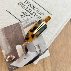 Detailed close-up of a tortoise shell acetate hair clip with gold metal and French engraving