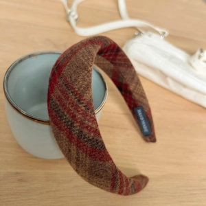 Retro red-brown tweed plaid wide headband with hand made label on a wooden desk