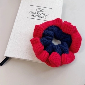 Chouchou en laine tricotée rouge et bleu foncé contrasté posé sur un livre blanc