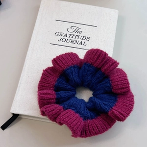 Détail d'un chouchou en maille avec centre bleu marine et bords roses côtelés sur carnet