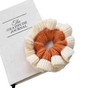 Chouchou tricoté doux avec contraste orange et beige sur un livre blanc