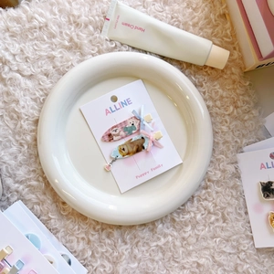 Dettaglio di dolci fermagli per capelli con fiocchi e motivi di cuccioli su carta