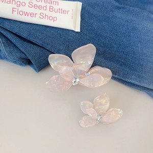 Haarklammern aus rosa Acetat in Blumenform mit glitzernden Strasssteinen auf Denim