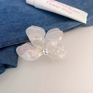 Makrodetail einer perlmuttfarbenen Blumen-Haarklammer mit Kristall auf Denim-Stoff