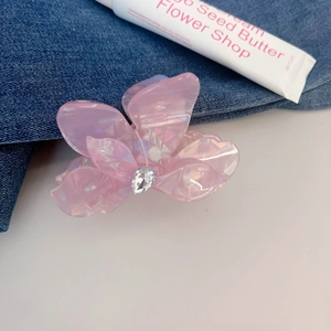 Makroaufnahme einer rosa Acetat-Blütenhaarklammer mit Tropfen-Strass auf Jeansstoff