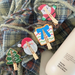 Festliche Weihnachts-Haarspangen mit Weihnachtsmann und Geschenk auf grünem Schal