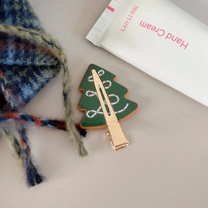 Detailansicht der Weihnachtsbaum-Haarklammer mit Festtagsmuster auf warmem Strickstoff
