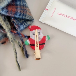 Nahaufnahme der süßen Weihnachtsmann-Haarklammer mit goldenem Entenschnabel-Clip und bunten Farben