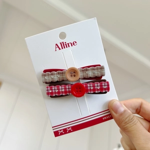 Close-up of red and brown plaid hair clips with decorative buttons and rhinestones