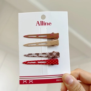 Detailed close-up of a 4-piece set of red and brown patterned metal hair clips on a card