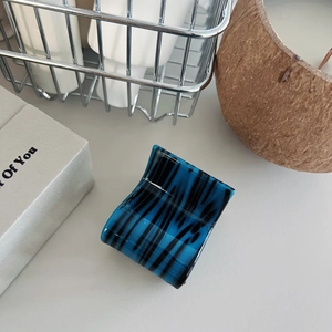 Close-up of elegant deep blue and black striped hair claw clip in acetate material