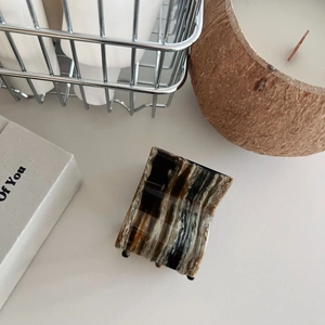 Close-up of square hair claw clip with brown marble texture in minimalist lifestyle setting