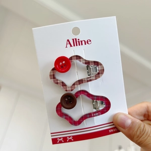 Detail of wavy red and brown plaid hair clips with buttons on a display card