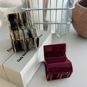 Detail of square hair claws in marble acetate and glossy deep red finish