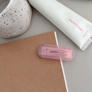 Detailed view of a pink translucent rectangular hair clip clipped onto a paper notebook