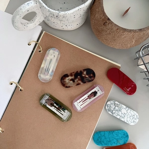 Detailed view of handmade acetate rectangle hair clips in multiple colors with gold logo