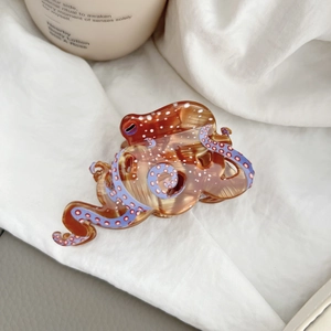 Detail showing the amber-colored octopus hair claw clip with purple tentacle patterns