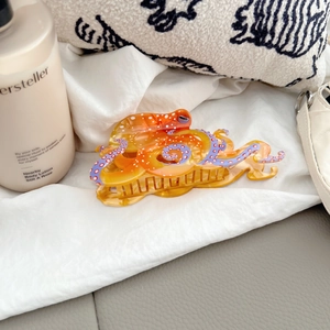 Detailed shot of an octopus hair claw clip in orange with purple suction cup accents