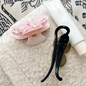 Pince à cheveux fleur rose en acétate avec strass et barrette noire sur tapis doux