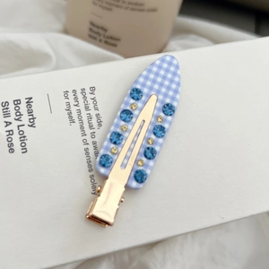 Detail der blau-weißen Karo-Haarklammer mit funkelnden blauen und gelben Kristallen