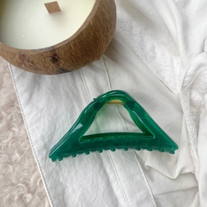 Detailed view of an emerald green hollow triangular hair claw clip with golden spring