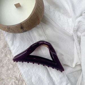 Macro shot of large purple triangular hair claw clip with golden metal spring details