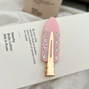 Detailansicht einer rosa Haarspange mit weißen Strasssteinen auf weißer Box