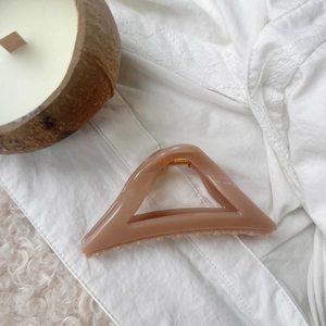 Detail of pink geometric triangle hair claw clip with golden spring on lace background