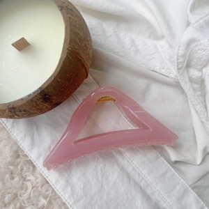 Macro shot of pink triangular hollow hair claw with gold spring on lace fabric
