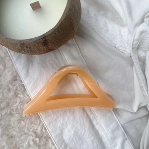 Detailed view of the apricot resin shark hair claw clip with a hollow triangle design