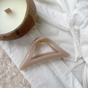 Detailed view of large translucent cream triangle hair claw clip with golden spring mechanism