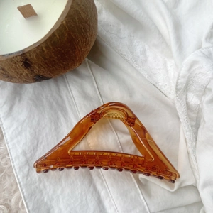 Detail of amber translucent hair claw clip with golden spring on lace fabric