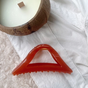 Detail shot of a transparent amber triangle hair claw clip on a soft textured background