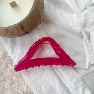 Macro shot of large shiny magenta hair claw clip on soft fabric and lace background