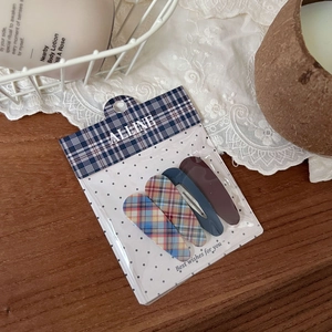 Set of four cute hair clips in red-blue plaid and solid matte colors on a card