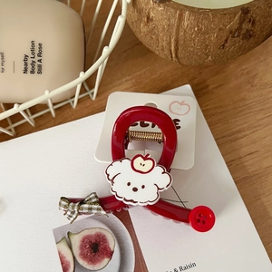 Detalle de una pinza para el pelo roja con un perrito blanco y un diseño de mini manzana
