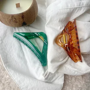 Detail of transparent amber and emerald triangle hair claws with gold metal springs