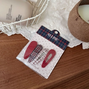 Set of four red plaid and solid color hair clips on a vintage wooden background