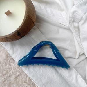 Detail view of large dark blue triangular hair claw clip on lace and rug