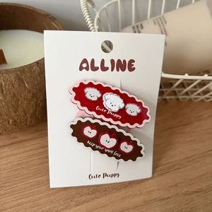 Detalle de pinzas de pelo con motivos de perro y manzana sobre tarjeta y mesa de madera