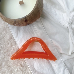 Macro shot of large orange geometric hair claw clip with marble texture and gold spring