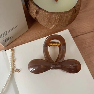 Détail de la pince à cheveux élégante en résine ambre brillante avec nœud chic