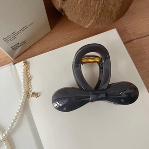 Gros plan sur la pince à cheveux nœud gris foncé de 8cm avec ressort doré et fini brillant