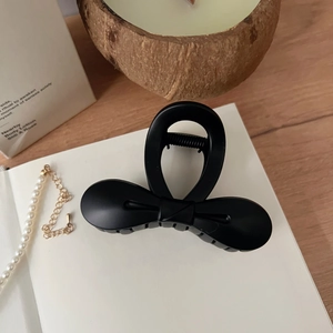 Détail d'une pince à cheveux nœud noir mat de 8cm avec mécanisme à ressort élégant